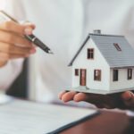 Man hold a tiny house and a pen