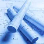 Rolled up blue architectural blueprints and technical drawings for a construction project.