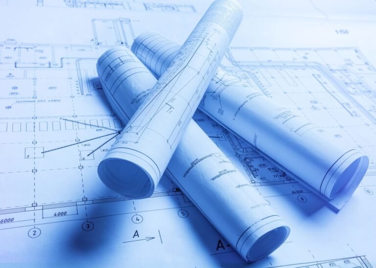 Rolled up blue architectural blueprints and technical drawings for a construction project.